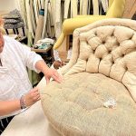 Hélène Navarre, experte internationale en tapisserie d’ameublement, posant dans son atelier avec une chaise en cours de restauration.