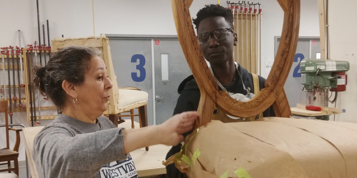 Mona Séguin, ébéniste finisseur, explique la restauration à un étudiant dans le cadre d’un atelier de restauration et de tapisserie d’ameublement à l’ÉÉAM, à Montréal.