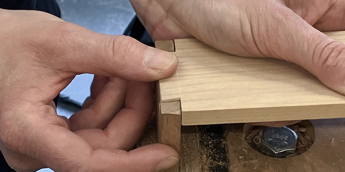Mains testant un assemblage à queue d’aronde en bois réalisés à l’École d’ébénisterie d’art de Montréal